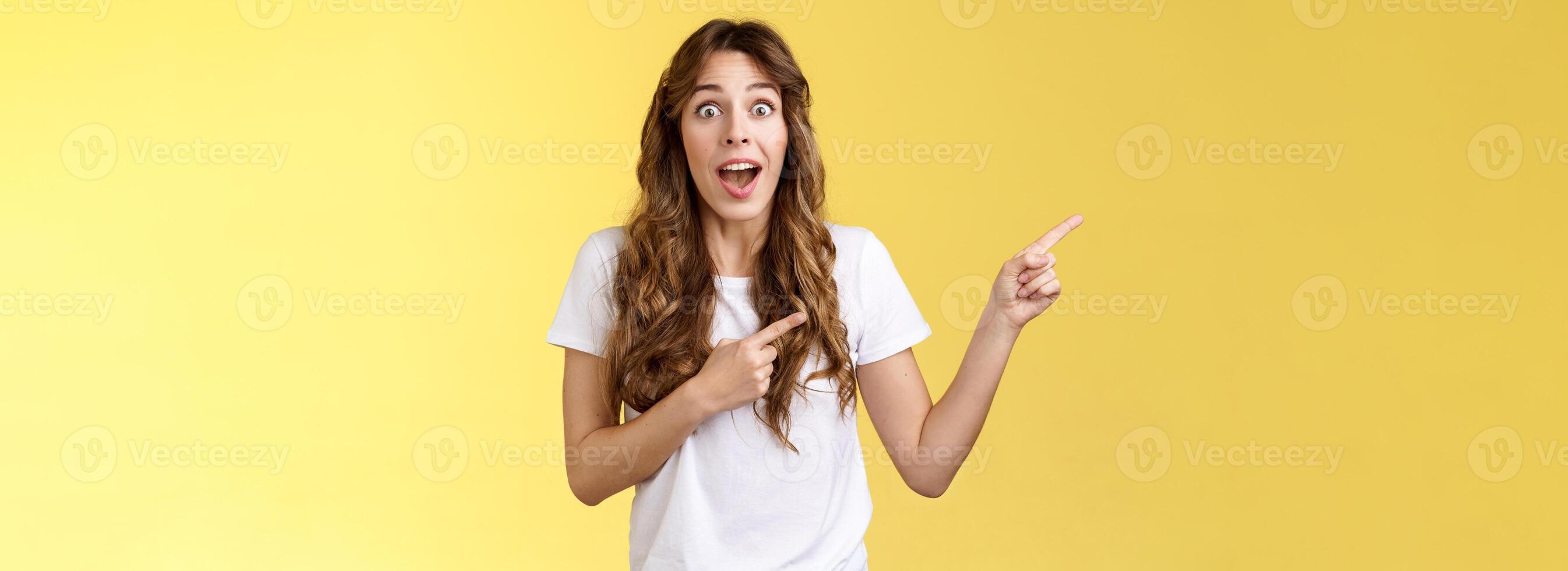 Excellent offer right behind corner. Amused surprised enthusiastic speechless cheering girlfriend scream impressed excited stare camera astonished pointing index fingers left yellow background photo