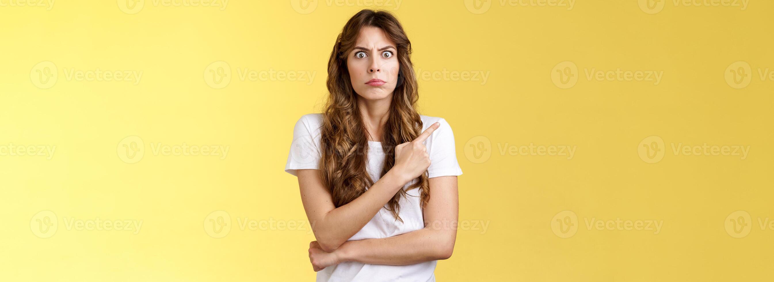 What he doing her. Intense displeased woman see ex-boyfriend behind back standing uncomfortable troublesome situation stare camera angry annoyed pointing upper left corner awkward moment photo