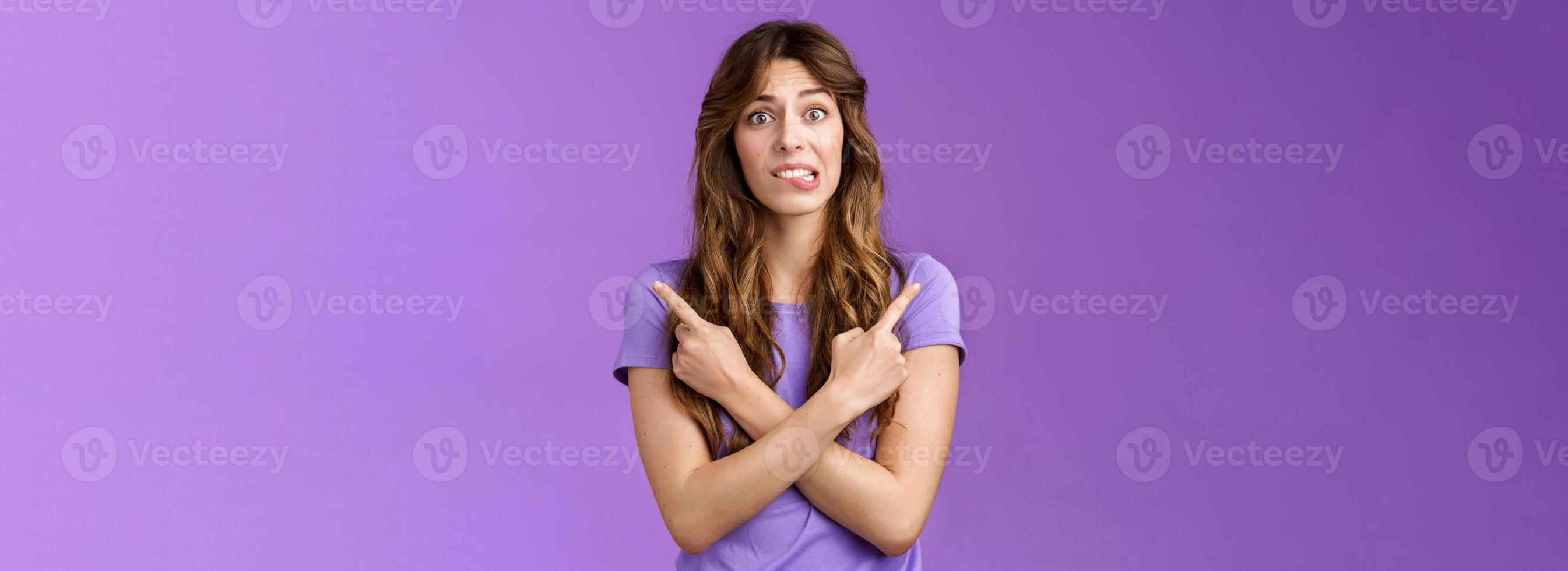Perplexed timid hesitant worried girlfriend afraid making bad choice cross hands pointing sideways indicating left right perplexed decide frowning pull hesitant face asking advice purple background photo