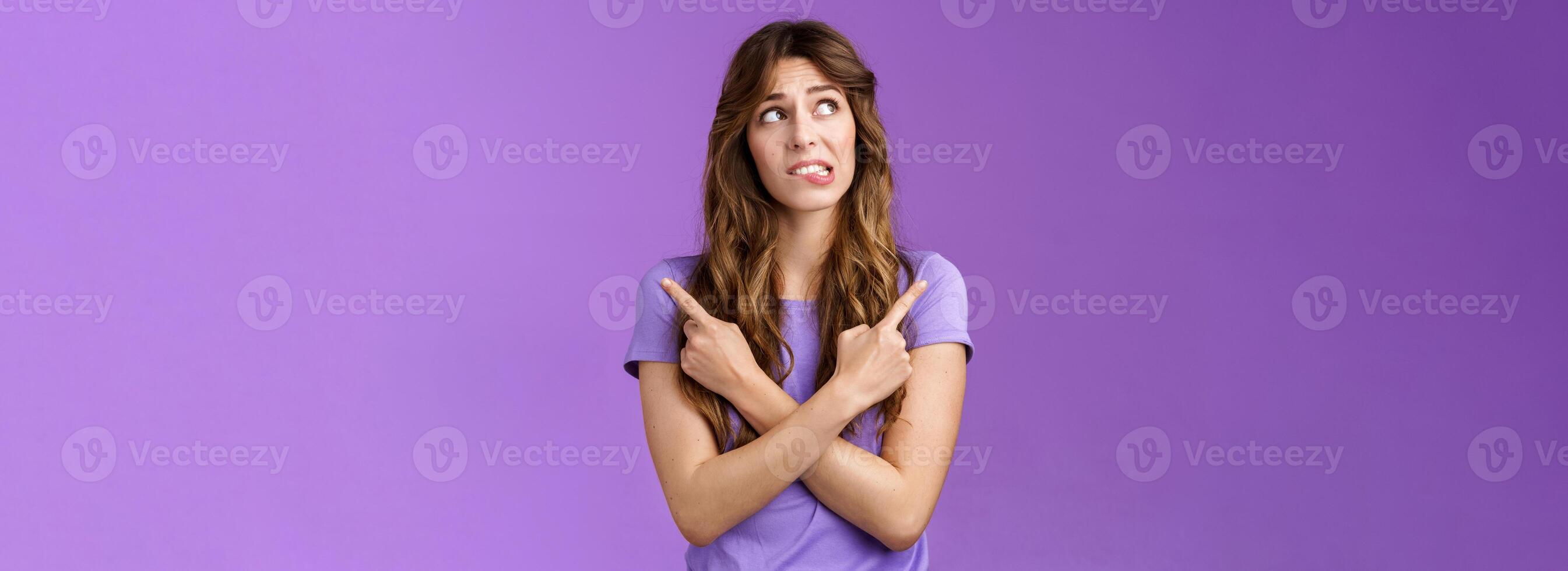 Hesitant unsure worried girl complicated make difficuly choice frowning nervously deciding look away pointing sideways cross hands chest left right anxiously choosing doubtful purple background photo