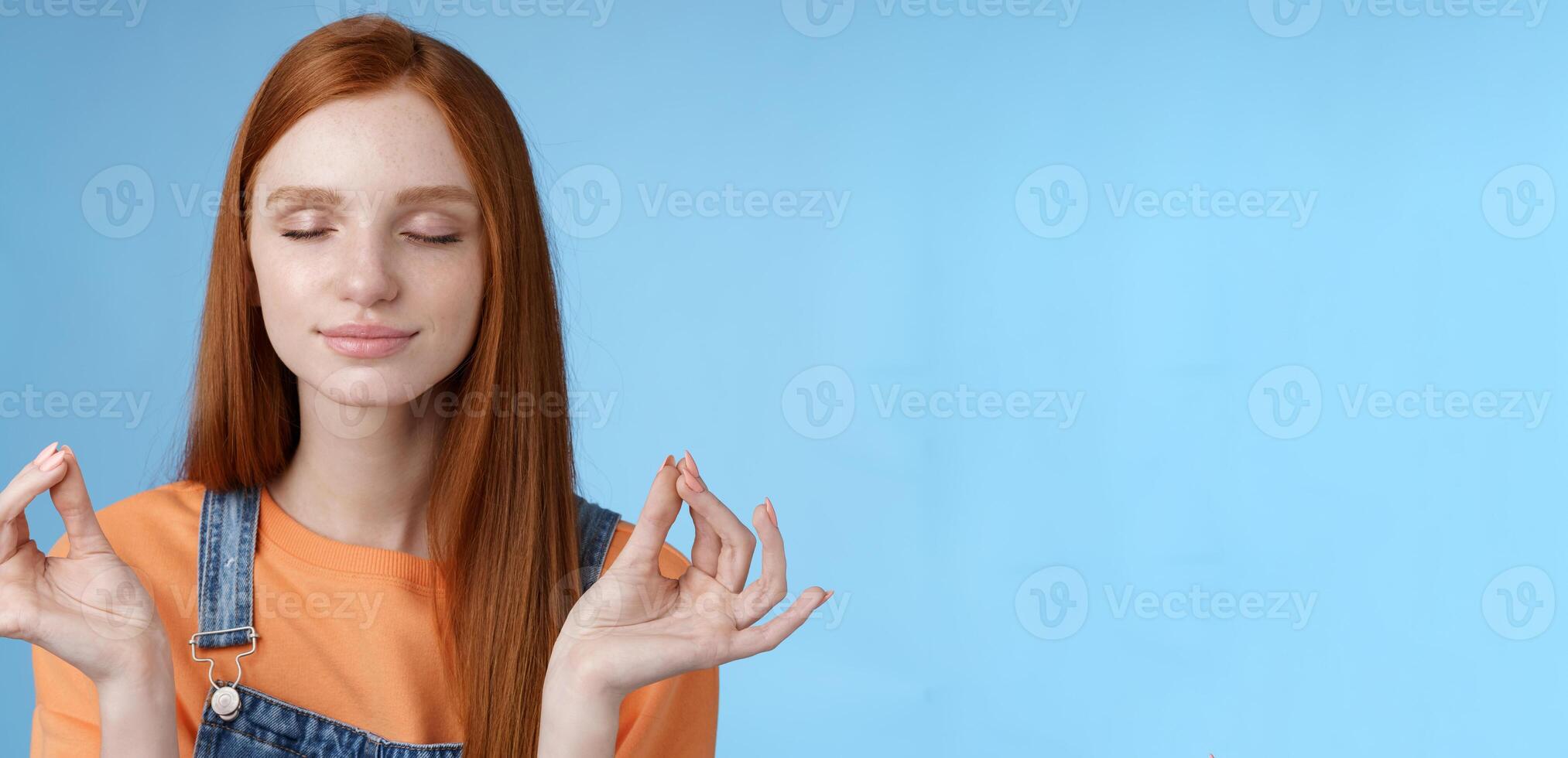 Keep calm redhead relaxed girl stay relieved positive close eyes smiling delighted raising hands sideways lotus mudra gesture practice yoga meditation do breathing exercise, blue background photo