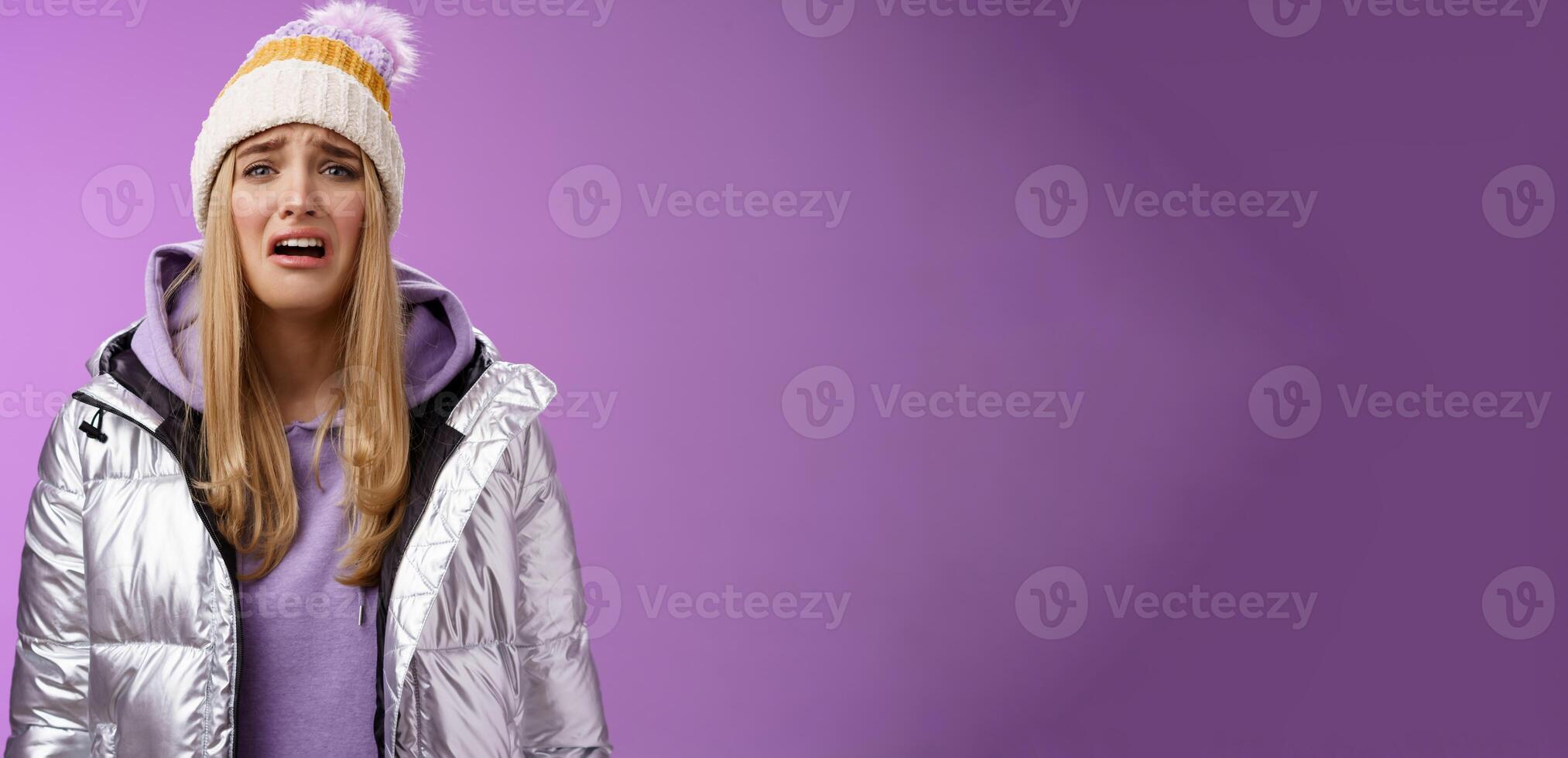 Upset sobbing miserable cute blond woman in silver stylish jacket hat crying whining unhappy feel sadness distress look disappointed complaining cruel life, unlucky standing purple background photo
