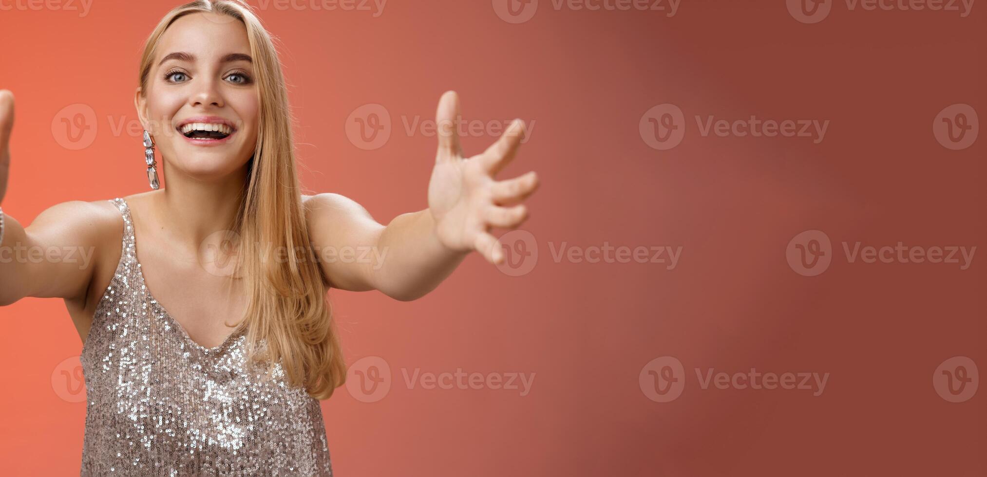 Hospitable charming nice young blond woman wanna hug come closer camera extend arms welcoming embracing cuddling being clingy smiling delighted standing amused red background photo