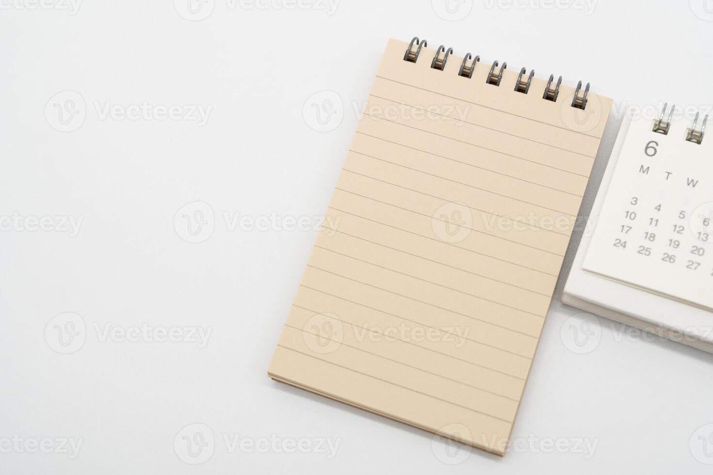 Empty Spiral notepad with brown lined papers and Simple desk calendar for JUNE in isolated background. Memo concept with copy space. photo