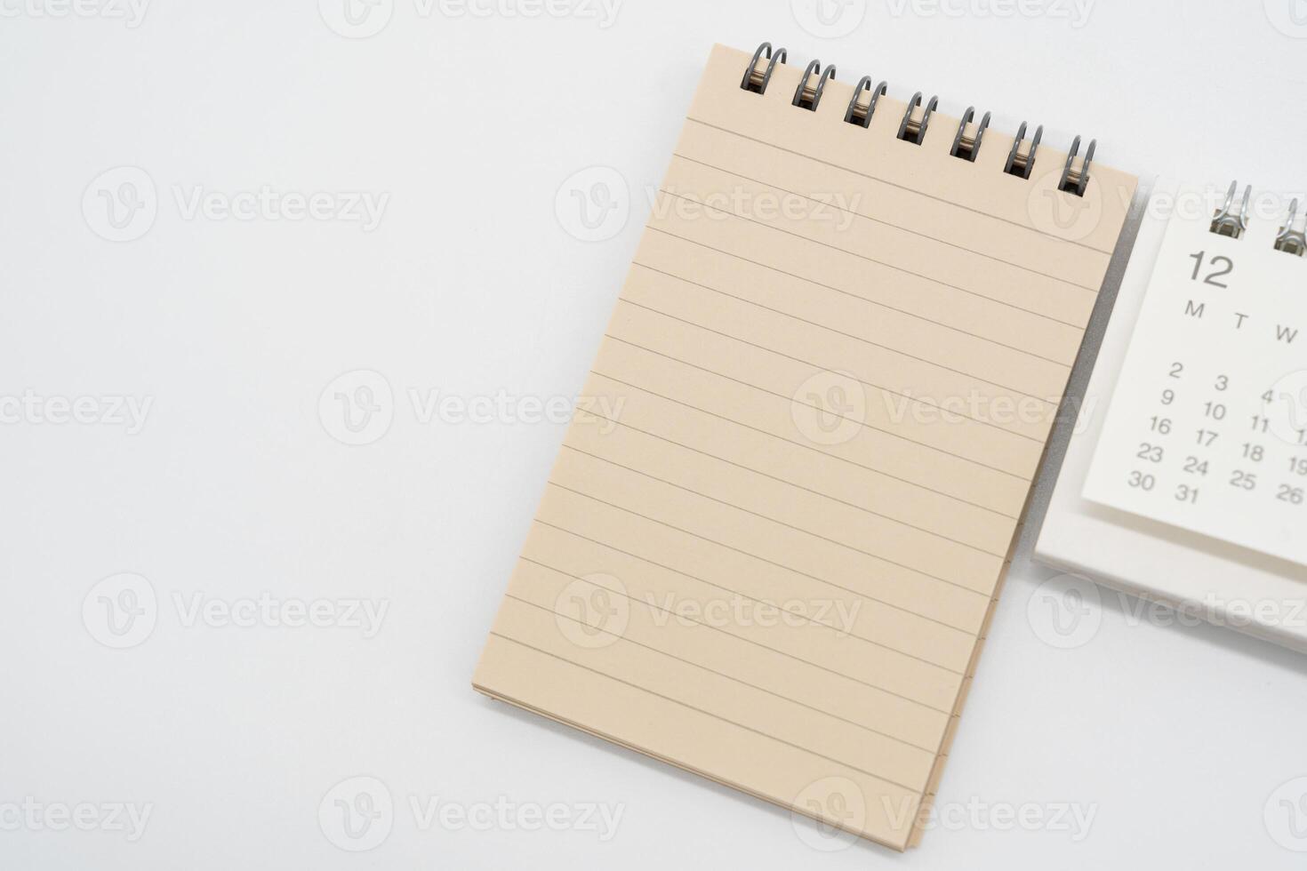 Empty Spiral notepad with brown lined papers and Simple desk calendar for DECEMBER in isolated background. Memo concept with copy space. photo