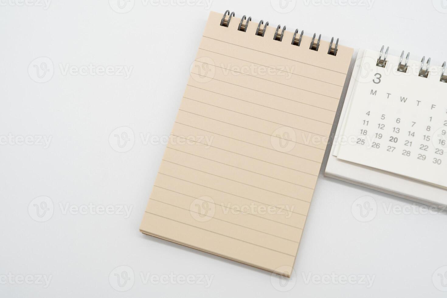 Empty Spiral notepad with brown lined papers and Simple desk calendar for MARCH in isolated background. Memo concept with copy space. photo