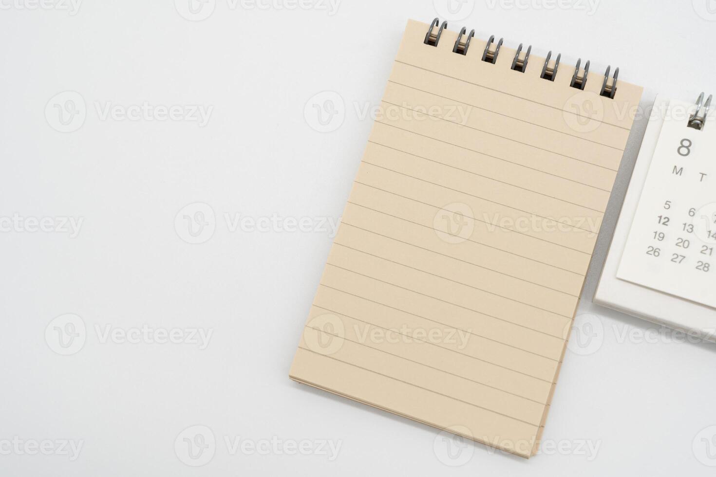 Empty Spiral notepad with brown lined papers and Simple desk calendar for AUGUST in isolated background. Memo concept with copy space. photo