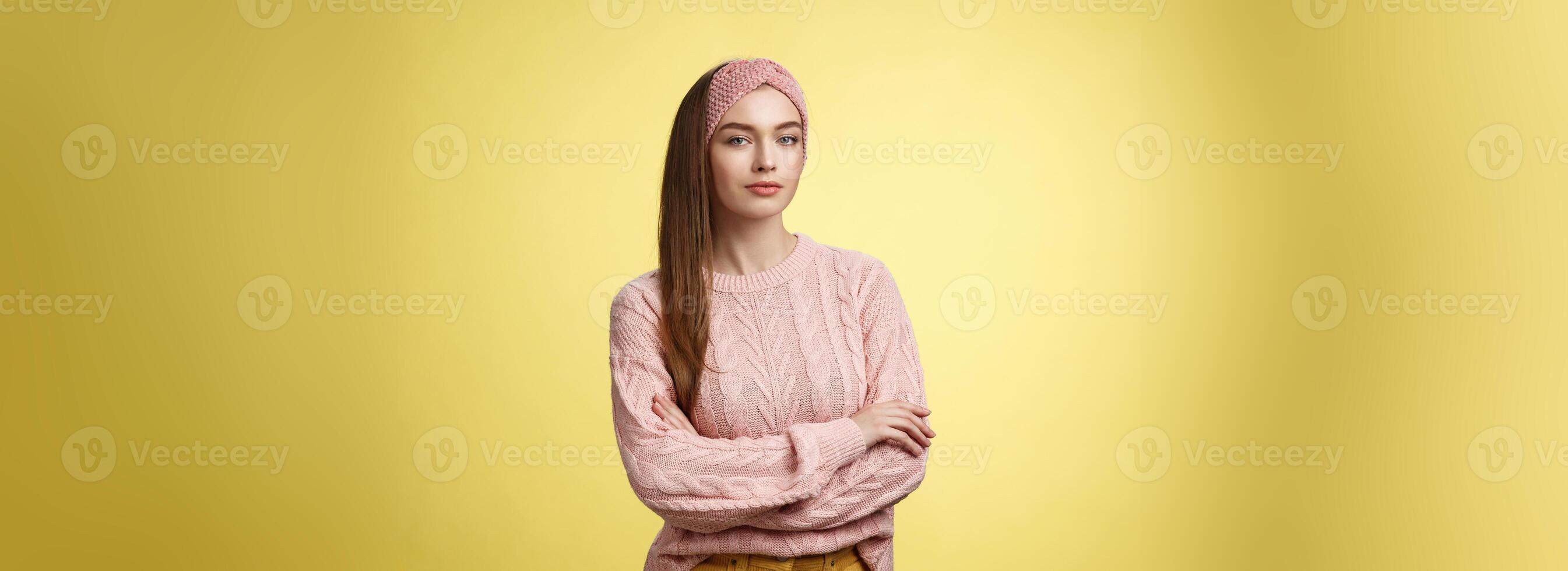 tratar a mí. confidente glamour joven hembra belleza salón gerente cruzar manos terminado cofre mirando confidente y descarado con seguro de sí mismo sonrisa afectada. niña estudiante posando en contra amarillo antecedentes alentado foto