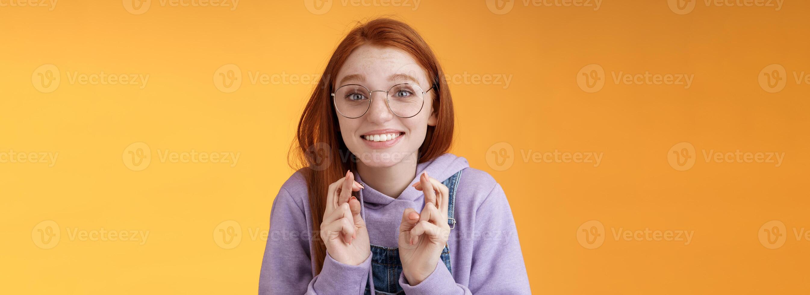 Hopeful young cute silly dreamy redhead attractive girl ginger straight haircut wearing glasses begging lord help cross fingers good luck desire win dream come true praying wish fulfill photo