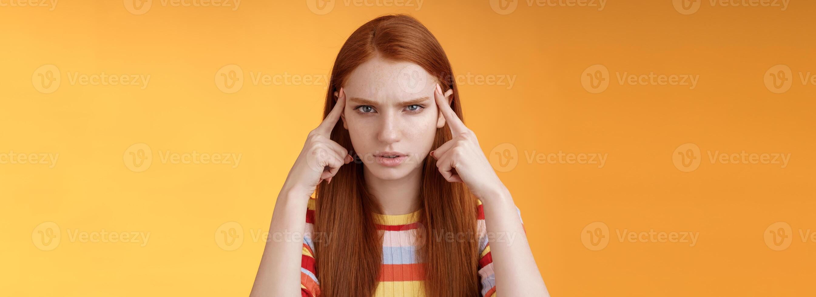 Puzzled serious-looking stressed-out young tired female student frowning look unhappy touching temples thinking trying focus, concentrate attention lecture memorizing hometask, orange background photo