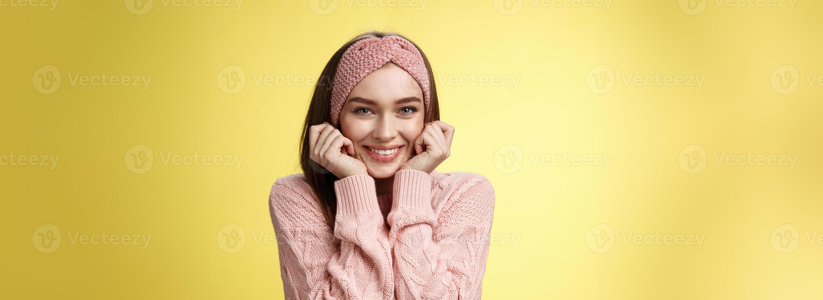Waist-up shot of silly glamour timid girlfriend in knitted sweater shining from joy and positive emotions, holding hands on cheeks delighted and pleased blushing joyfully, standing amused photo