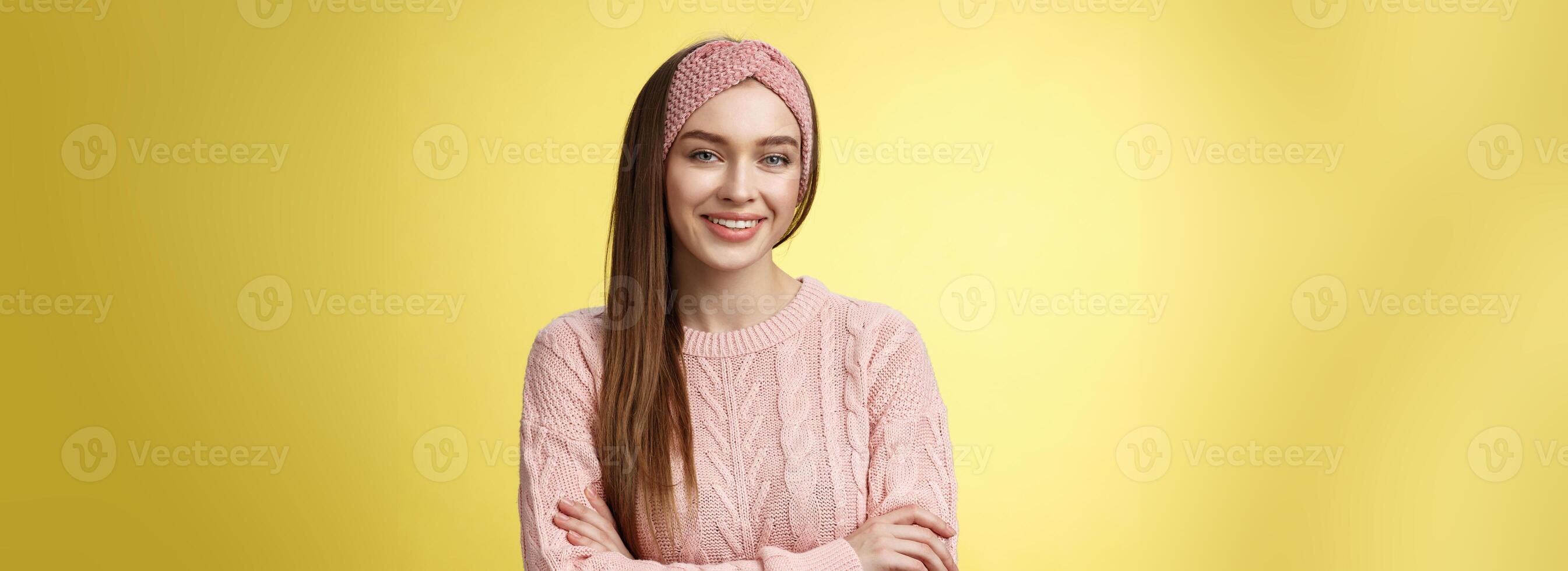 Waist-up shot of confident creative joyful cute european female model in knitted pink sweater, headband, cross arms self-assured, satisfied, smiling pleased and motivated, looking delighted photo