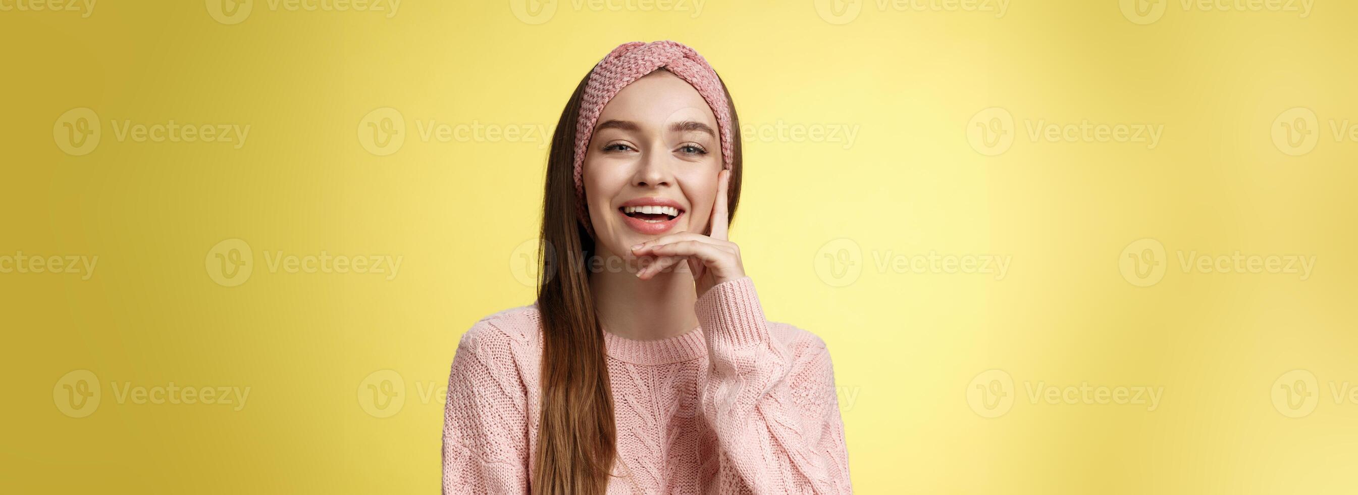 alegre entretenido joven atractivo europeo mujer en de punto rosado venda, suéter conmovedor mejilla sonriente, reír. estudiante con sonrisa en rostro, teniendo divertido, riendo terminado comedia película foto