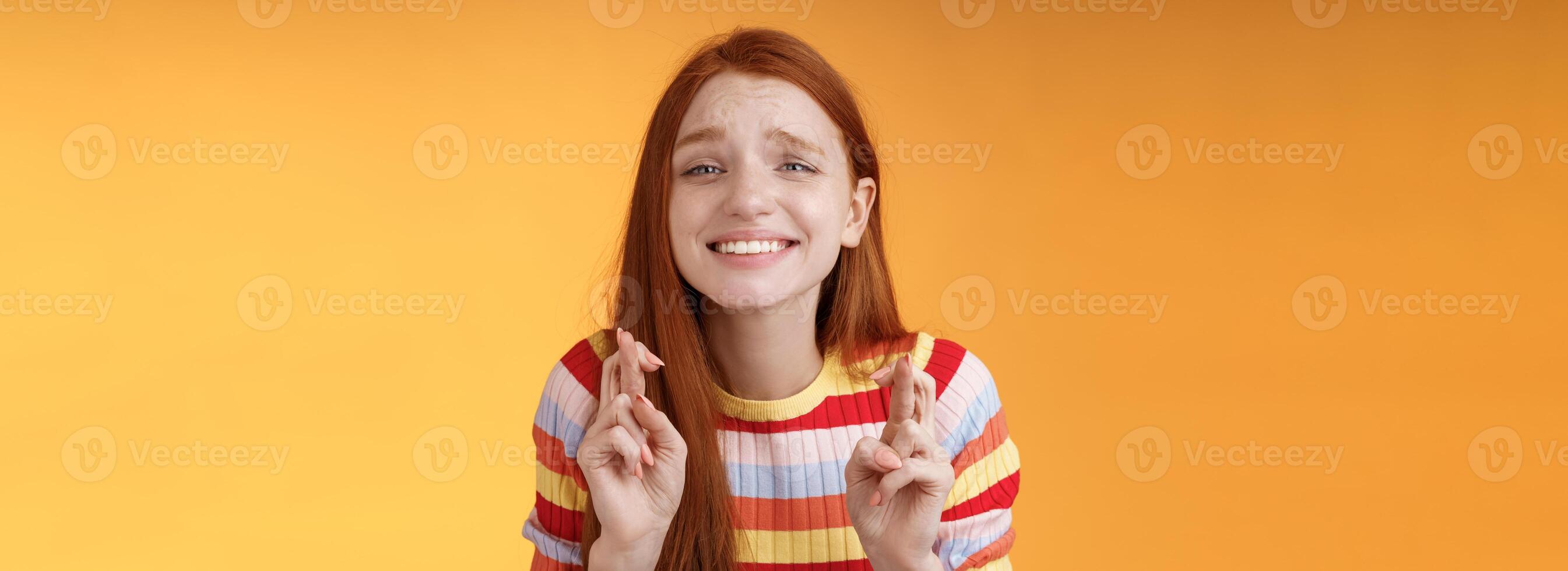 atractivo pelirrojo esperanzado niña anticipando bueno Noticias emoción emoción cruzar dedos bueno suerte sonriente en general Orando deseo ven cierto bueno resultados recibir premio, en pie naranja antecedentes deseo foto