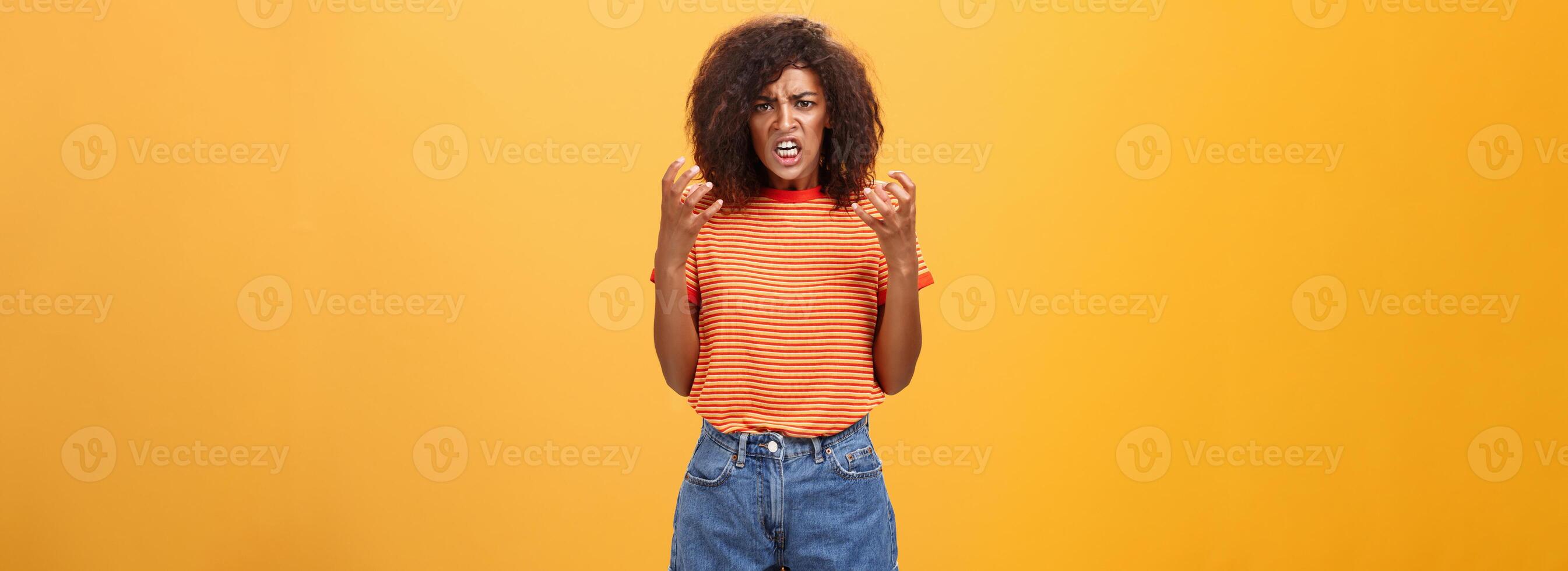 Woman going out of control feeling sick and tired ready to show rage and fury. Portrait of pissed and annoyed furious female clenching raised fists frowning and frimacing looking with scorn and hate photo