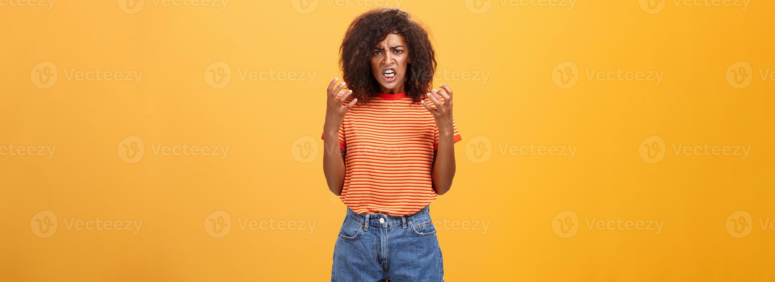 Woman going out of control feeling sick and tired ready to show rage and fury. Portrait of pissed and annoyed furious female clenching raised fists frowning and frimacing looking with scorn and hate photo