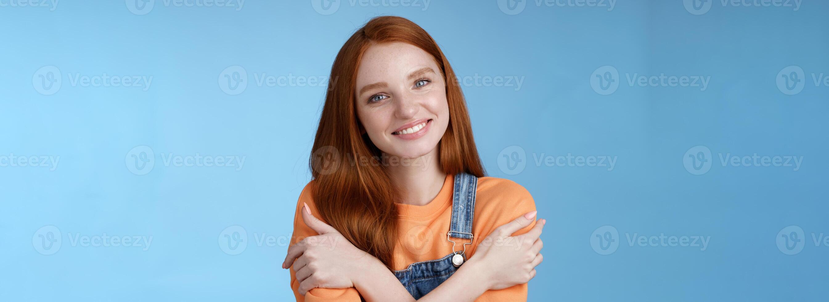 Tender silly redhead girl standing blue background smiling joyfully hugging arms crossed body feel chilly grinning delighted talking boyfriend romantic date asking lend jacket cold summer evening photo