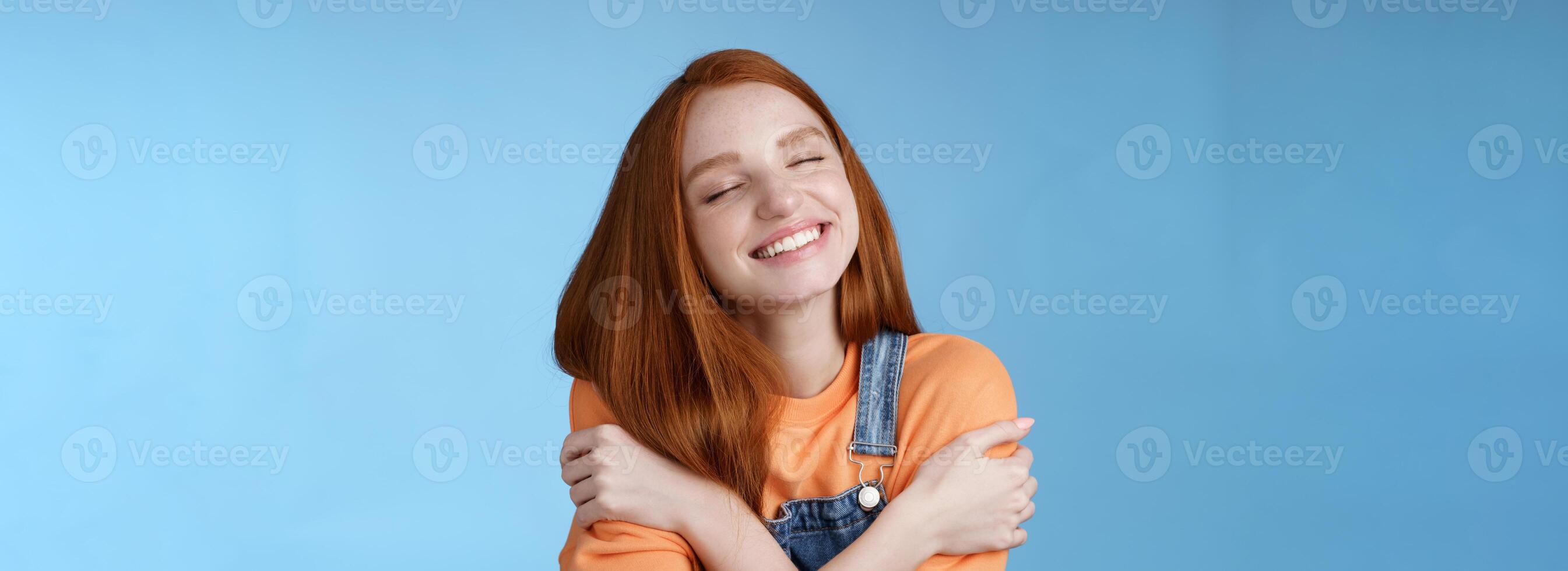 Close-up dreamy happy smiling redhead girl close eyes fantasizing romantic date grinning white teeth cuddle herself cross arms chest embracing recalling lovely memories hugging daydreaming photo