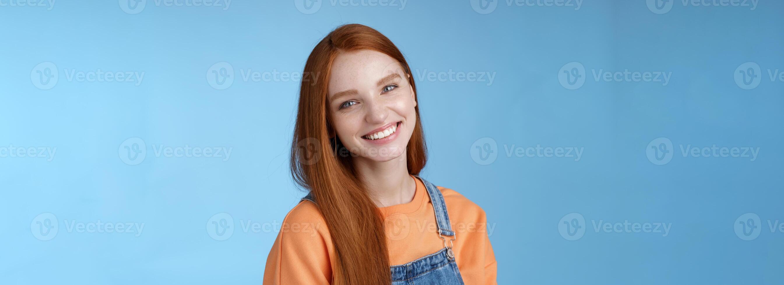 Pleasant sincere happy ginger girl blue eyes tilting head grinning happily laughing stay positive lucky spend time best friends receive praises compliments good job smiling delighted, blue background photo