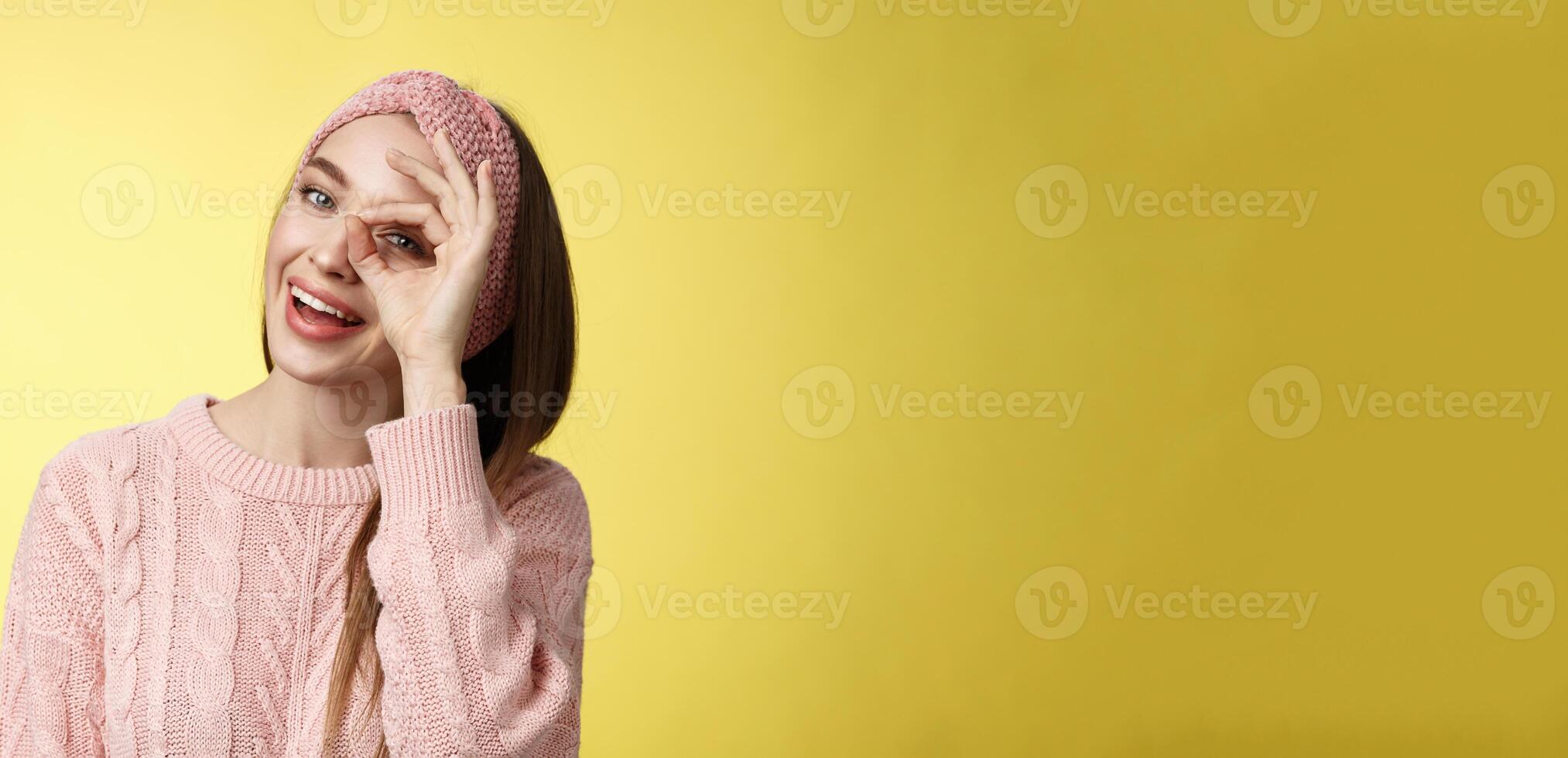 dejar yo ver cerca. linda glamour joven elegante europeo mujer vistiendo de punto suéter, venda inclinación cabeza alegremente sonriente intrigado positivo demostración circulo terminado ojo echar un vistazo a cámara juguetón foto