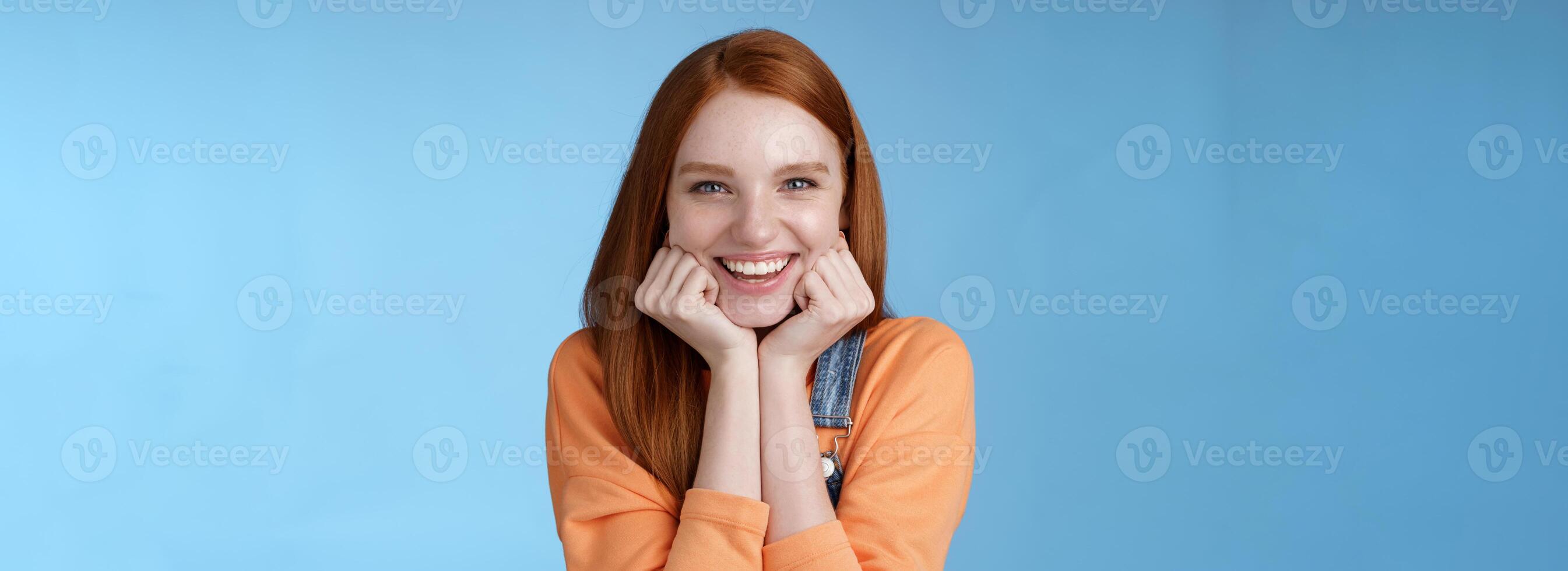 Enthusiastic sassy good-looking redhead caucasian girl lean head palms look amused intrigued listen interesting story pleased smiling laughing silly jokes standing blue background excited happy photo