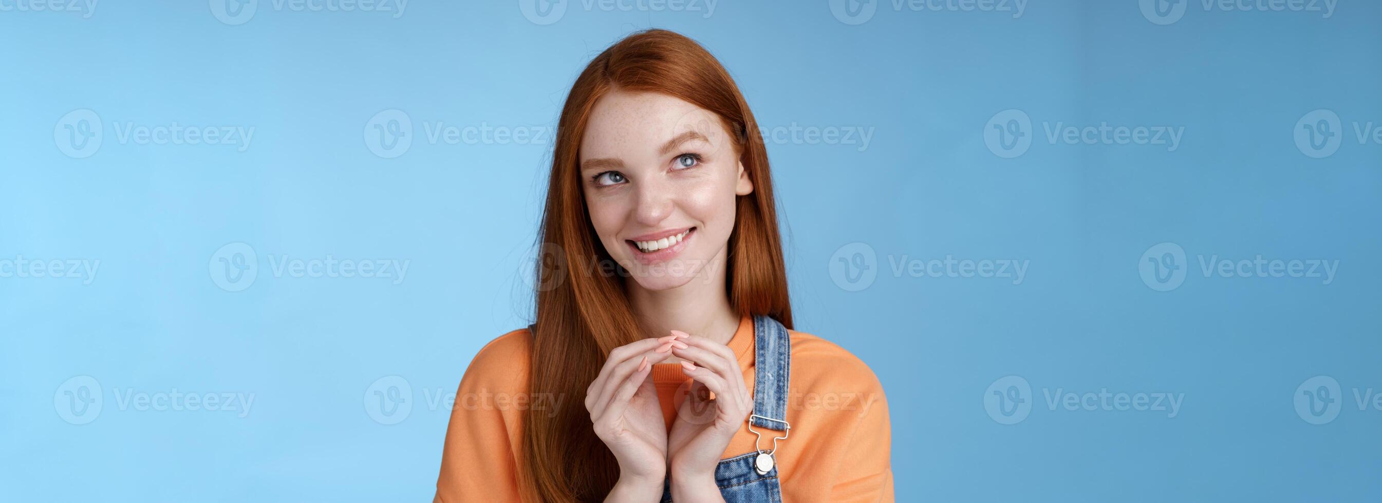 Devious tricky smart pretty redhead girlfriend have evil plan smirking mysteriously look upper left corner twiddles fingers think excellent plan, smiling delighted, standing blue background photo