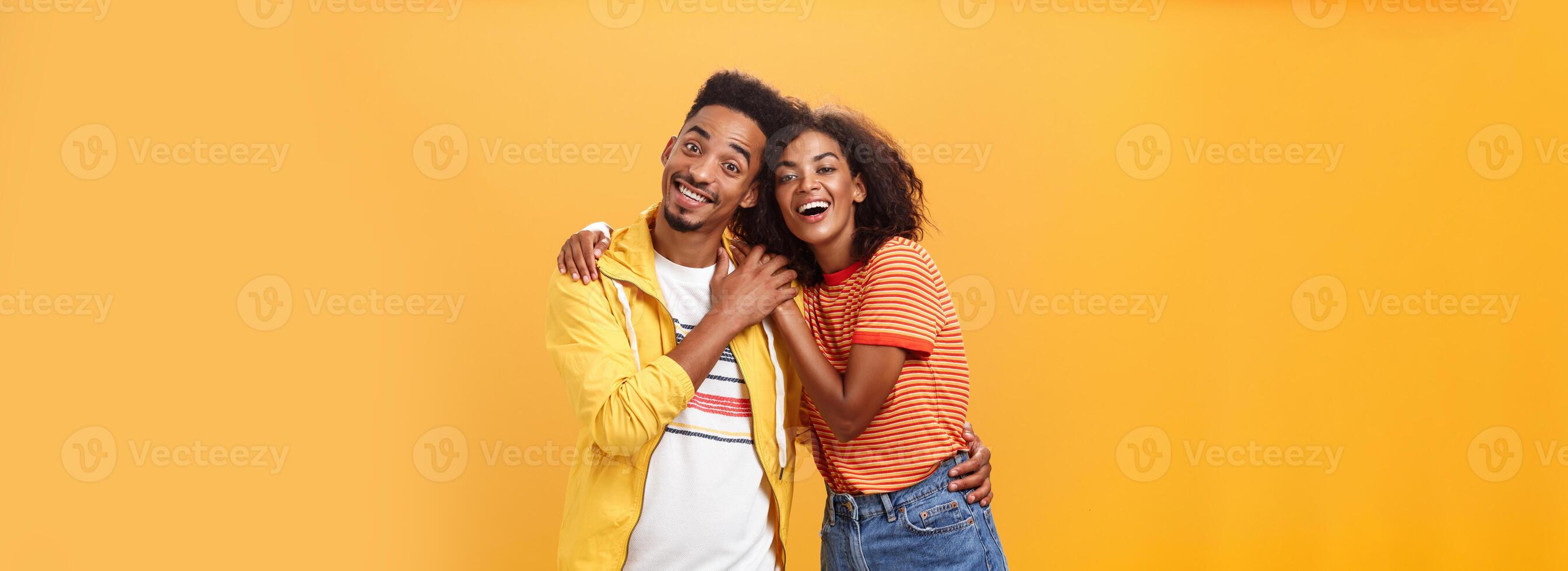 Friends always cover each other. Stylish and carefree loving african american girlfriend hugging boyfriend and smiling broadly touching guy palm hanging around and spending time great together photo