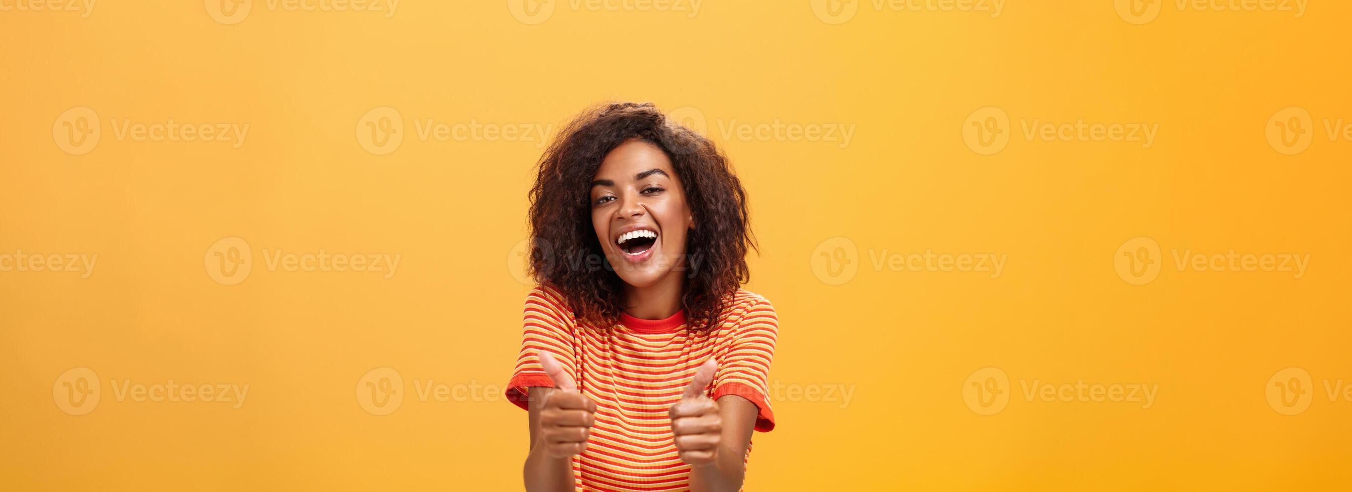Woman surely knows how boost mood. Portrait of friendly-looking stylish and outgoing african american girlfriend with curly hairstyle showing thumbs up in like and approval agreeing to friend idea photo