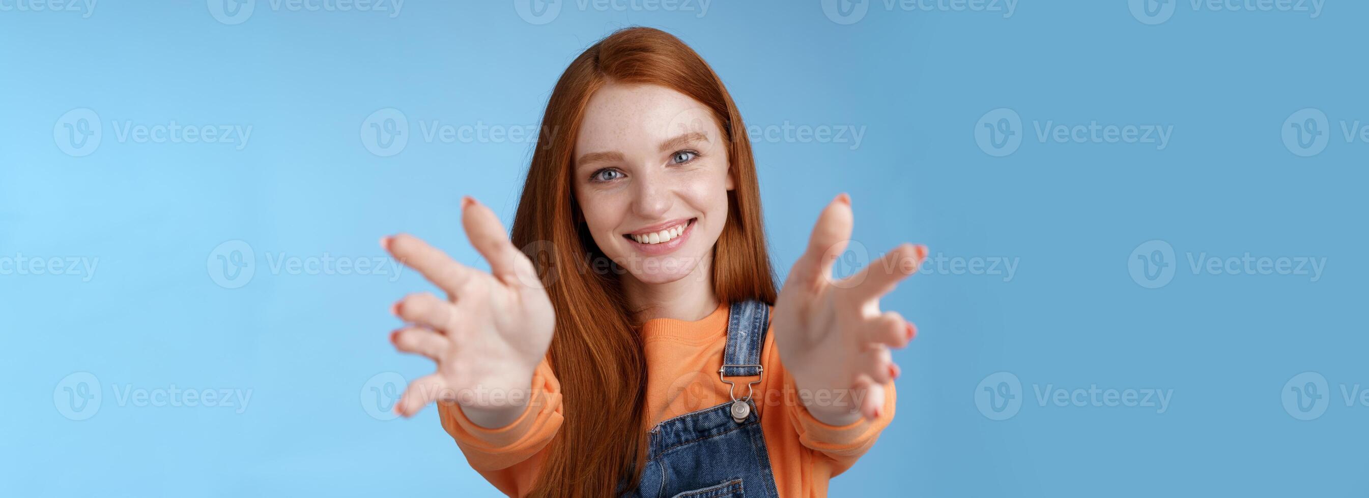 Come into arms. Charming sincere happy kind redhead girl baby sitting stretch hands camera wanna hold catch smiling friendly asking pass object, standing blue background reach friend give cuddles photo