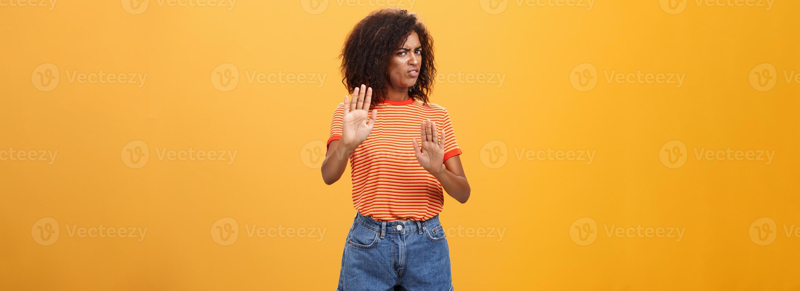 No yo rechazar. intenso suspicaz y disgustado inteligente afroamericano hembra rechazando malo oferta tracción elevado palmas torneado lejos con aversión y insatisfecho Mira en contra naranja antecedentes foto