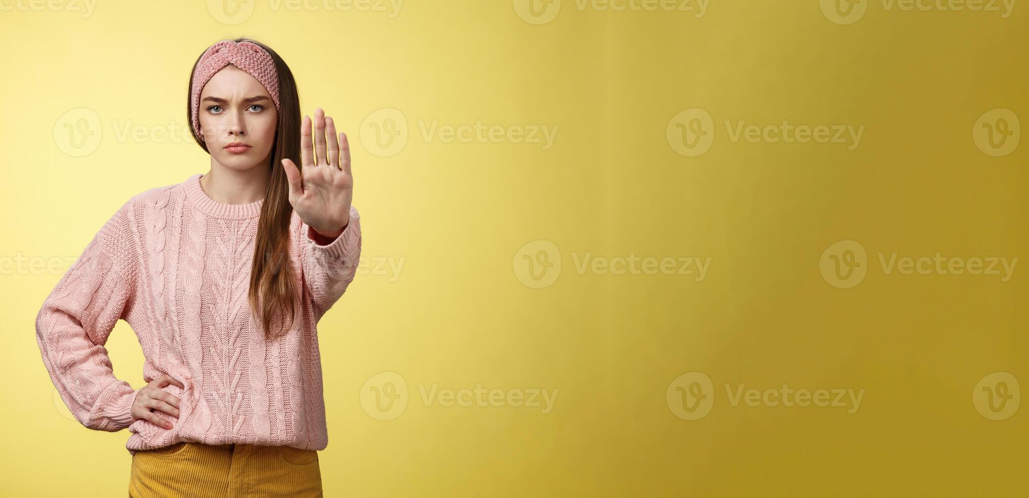 detener él. de aspecto serio confidente enfocado joven linda niña extensión brazo sostener, tresspass gesto, ceñudo disgustado, en pie mandón negando, amenazante aprobar, reacio Dejar pasar terminado amarillo pared foto