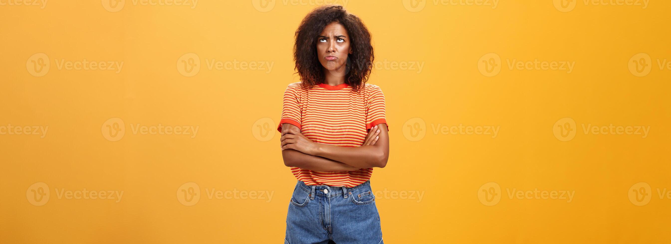 Why life so unfair. Portrait of cute offended and gloomy displeased african american young woman with afro hairstyle sulking pouting crossing arms on chest looking up with envy or jealousy photo