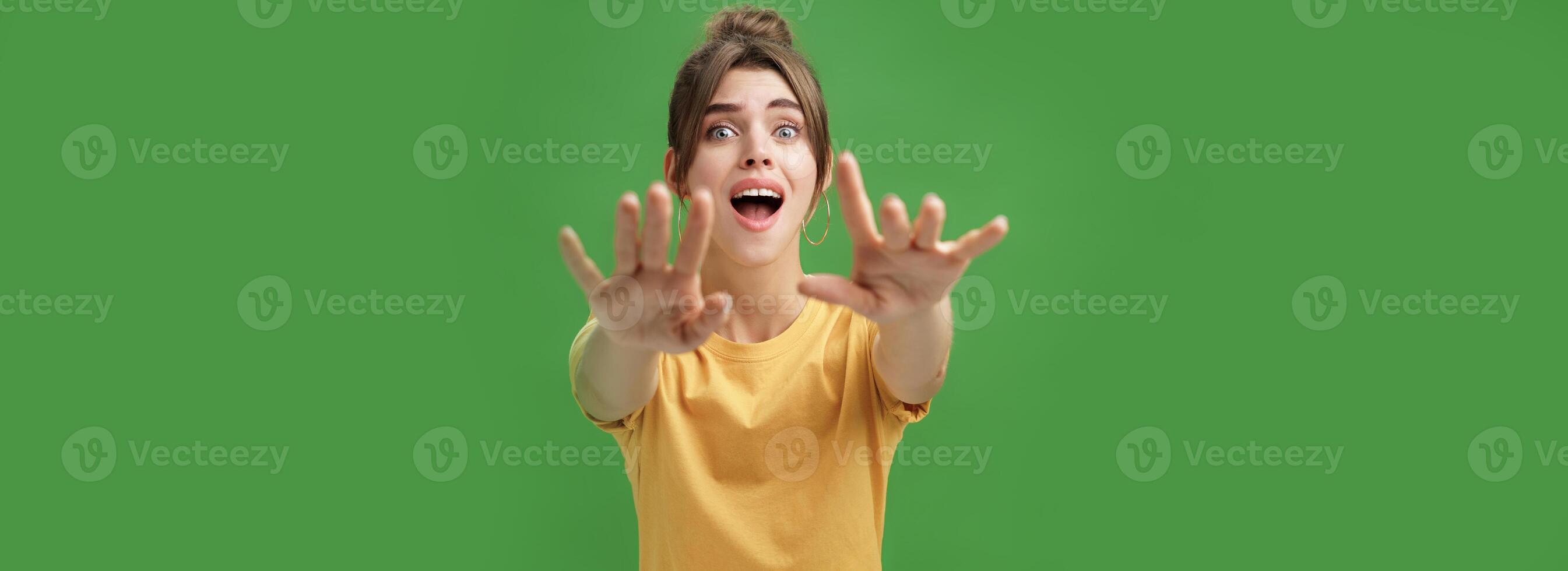 Excited and addicted goog-looking young woman reaching hands forward to camera with reckless look wanting grab something she desire seeing thing she wanted for long time over green background photo