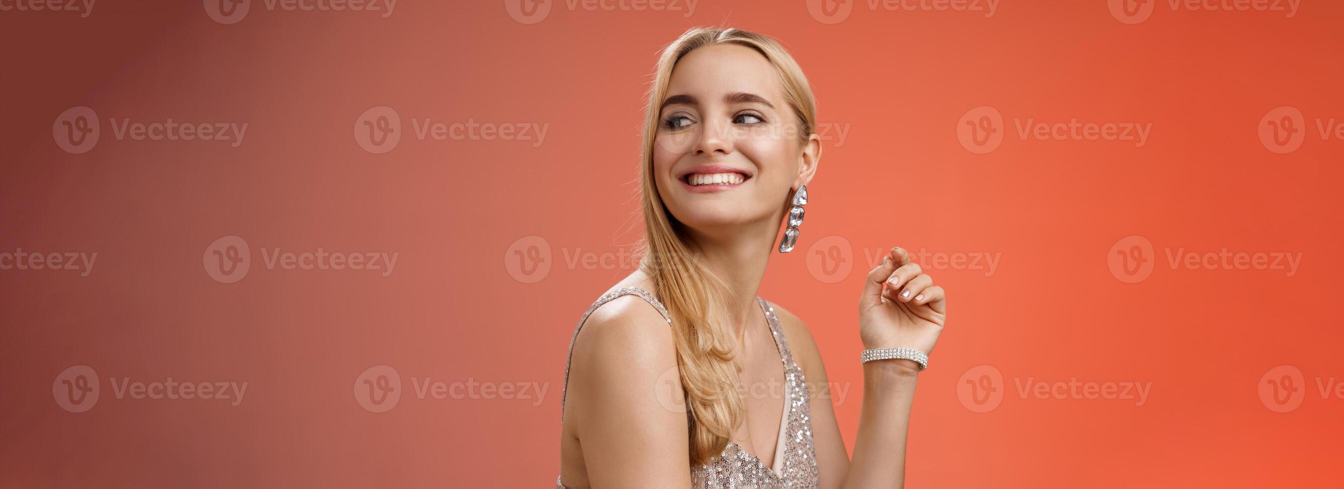 Elegant glamour gorgeous young rich blond woman attend charity party in stylish silver glittering dress accessorize turning right smiling greeting familiar person grinning joyfully, red background photo