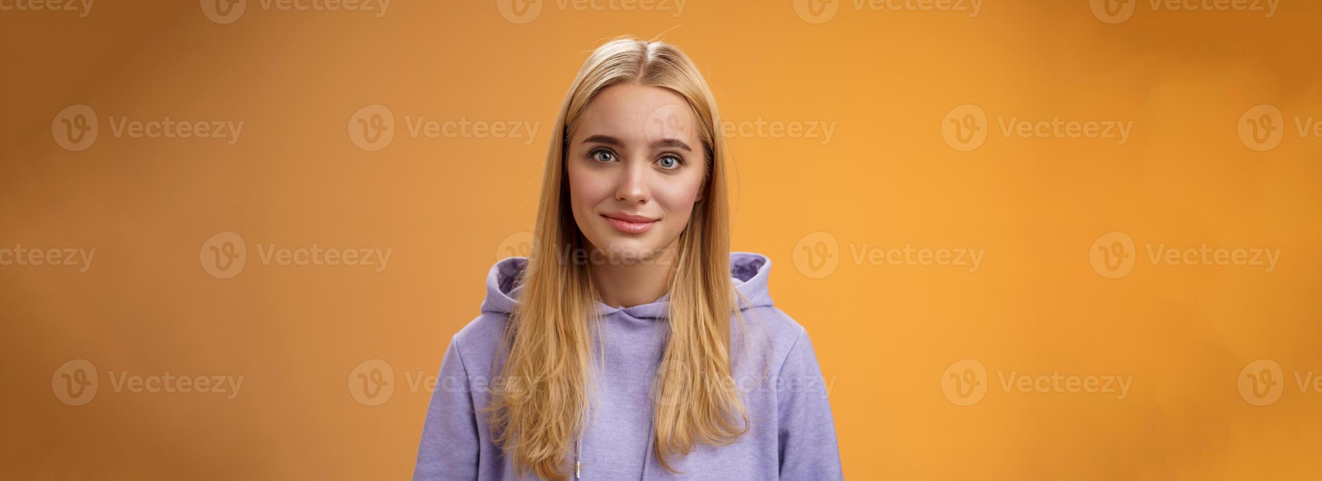 Waist-up delicate tender friendly-looking blond european girl in hoodie smiling supportive talking listening friends story nice interesting conversation standing casually orange background photo