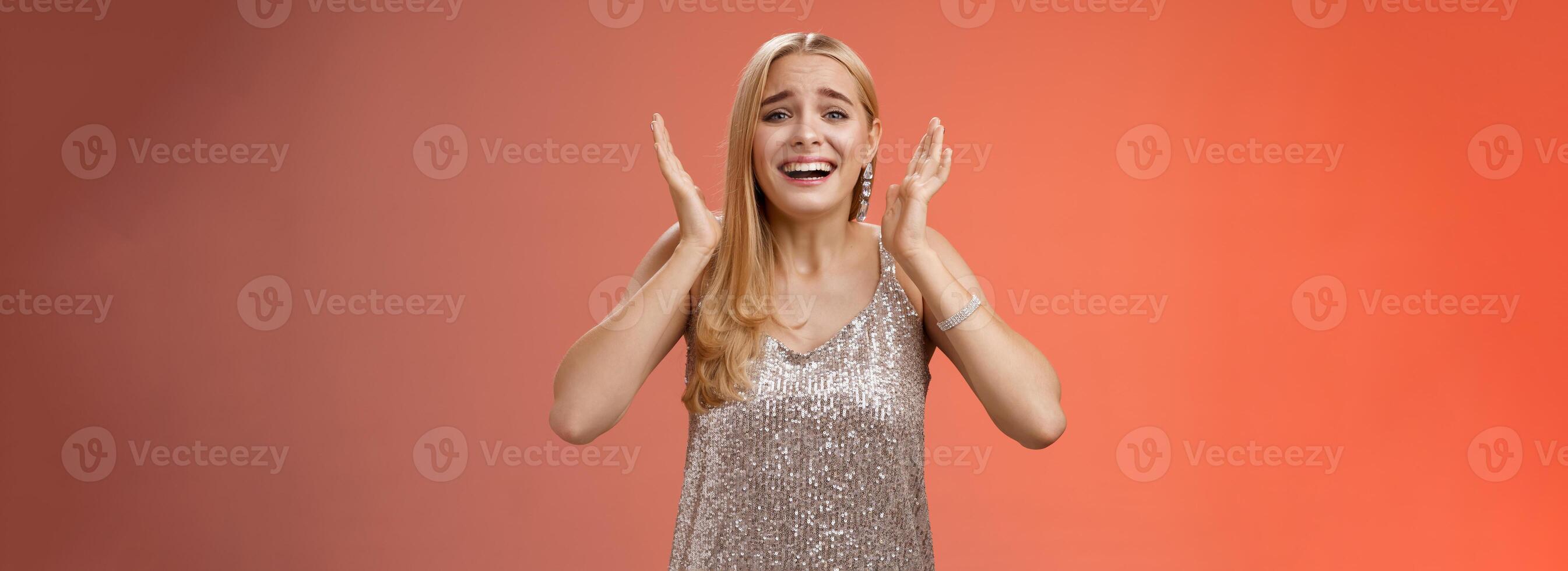 Amazed freaked out excited blond female fan see favorite celebrity star screaming astonished happy look emotive wanna cry happiness waving palms near head thrilled red background photo