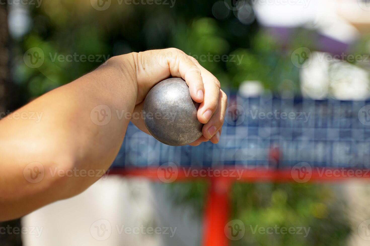 Players hold a petanque ball in their hands and prepare to throw the opposing team's petanque ball away from the target ball to begin placing the ball again. photo