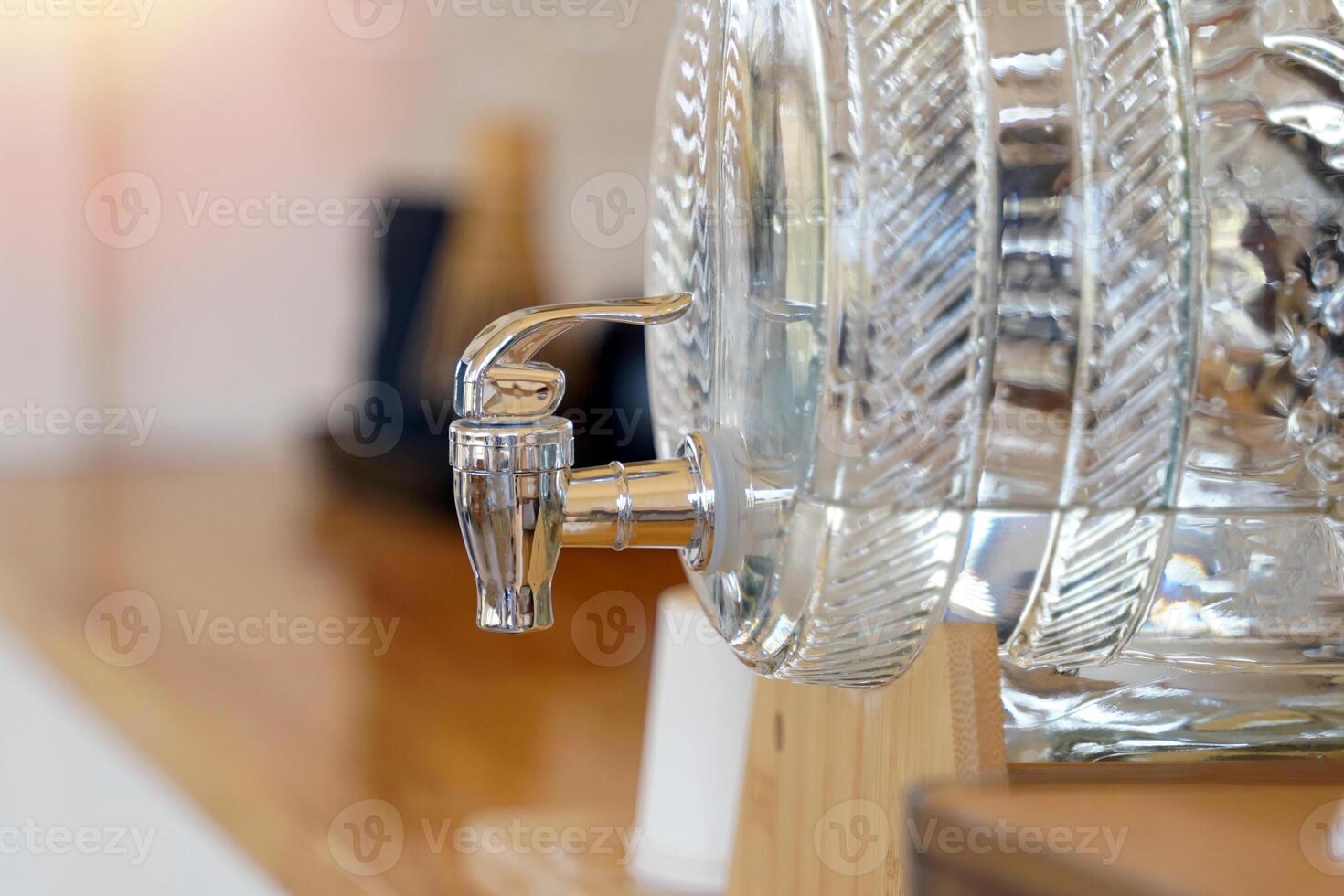 A glass water dispenser jar sits on the counter providing drinking water to coffee shop patrons or hotel restaurant. Soft and selective focus. photo