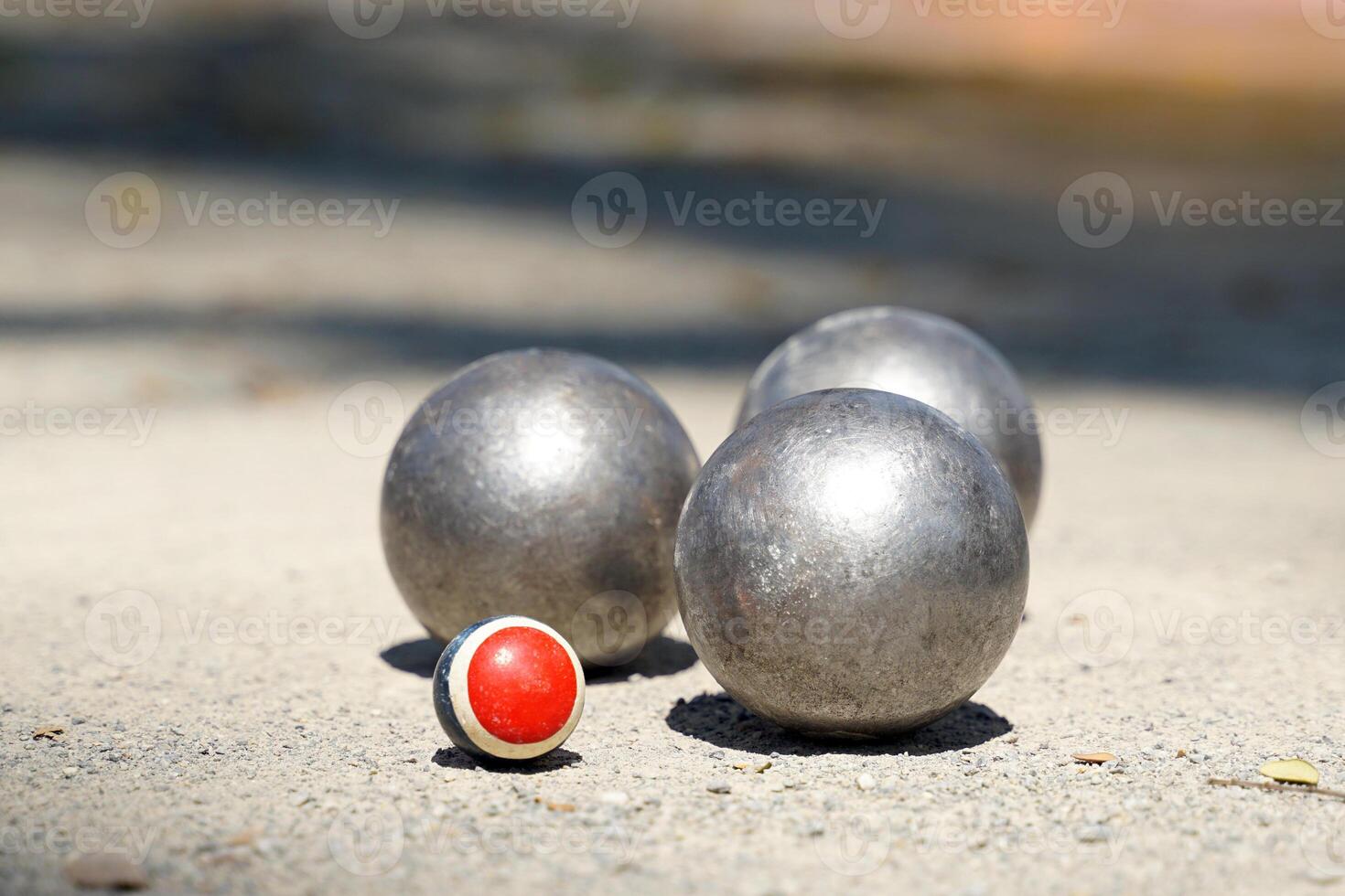 Petanque balls are placed near a target ball on an outdoor dirt field, where 12 round metal balls are thrown as close as possible to the target team that reaches 13. The first to score is the winner. photo