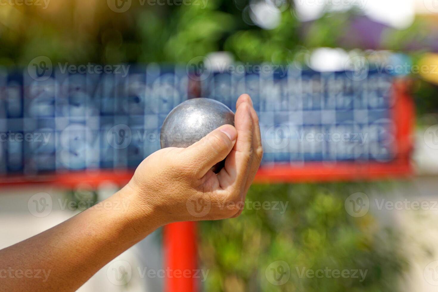 Players hold a petanque ball in their hands and prepare to throw it in order to place the petanque ball as close to the target ball as possible. photo