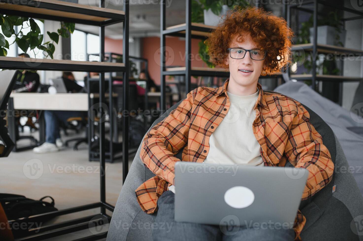 Caucasian hipster guy enjoying distance job in coffee shop, male freelancer in trendy glasses sitting in cafeteria with modern laptop device photo