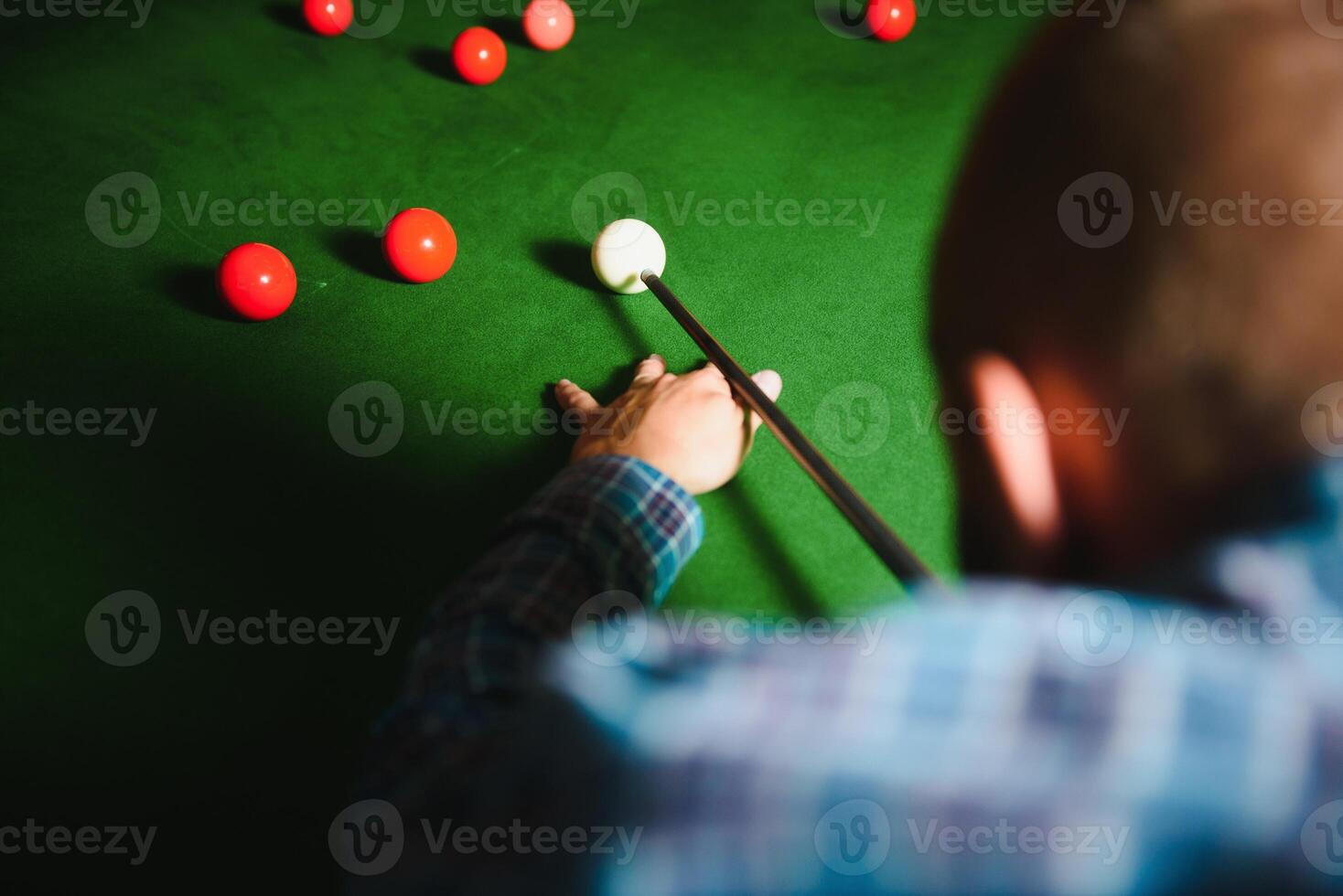 Young handsome man leaning over the table while playing snooker photo