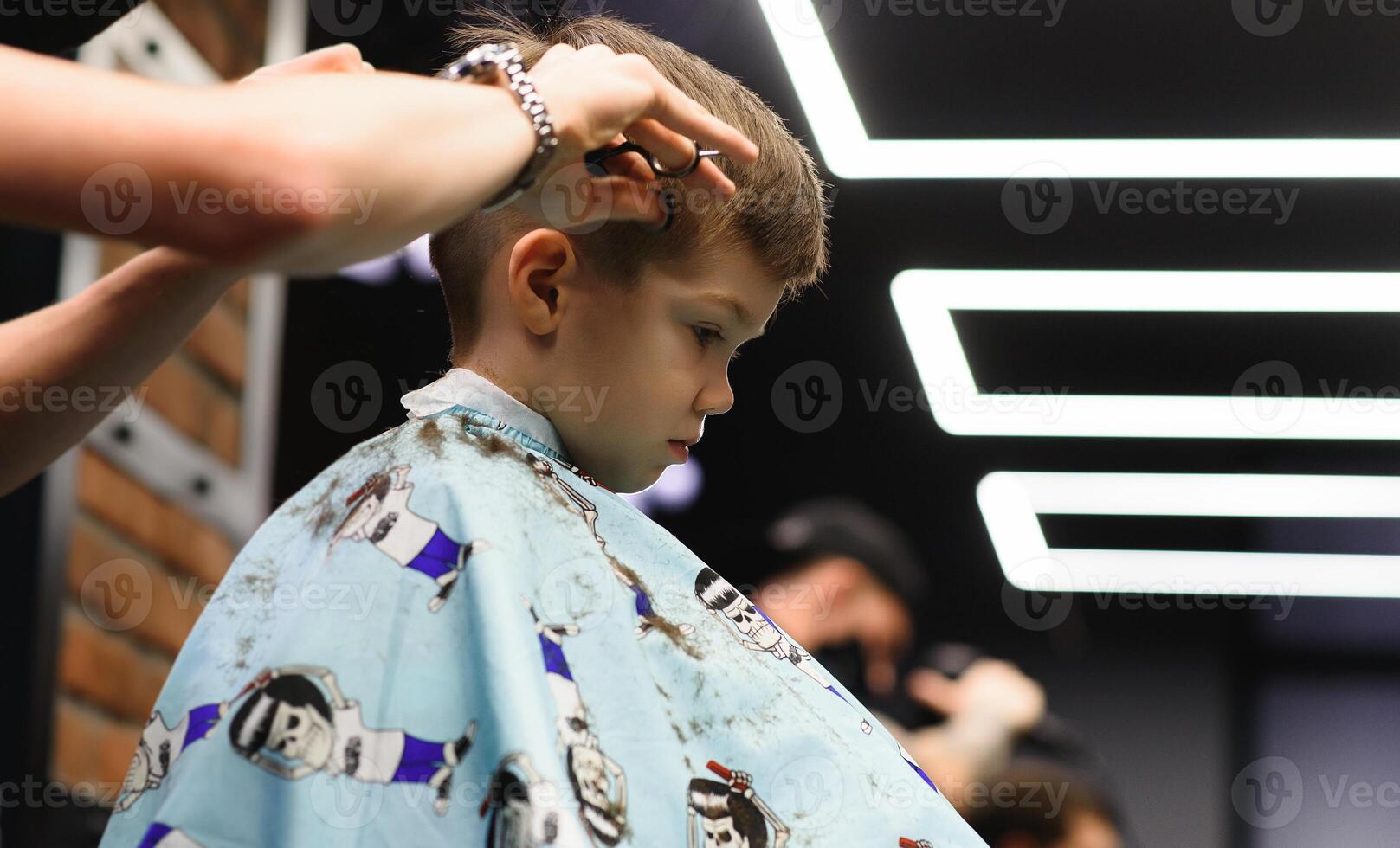 lado ver de linda pequeño chico consiguiendo Corte de pelo por peluquero a el peluquería. foto