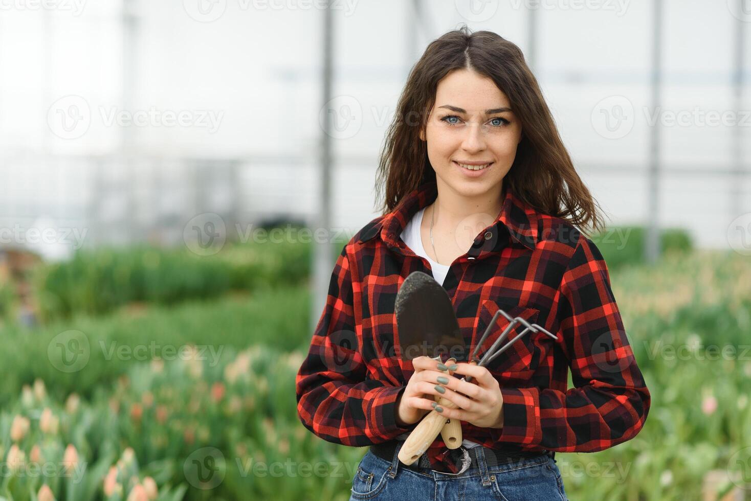 Beautiful young smiling girl, worker with flowers in greenhouse. Concept work in the greenhouse, flowers. photo