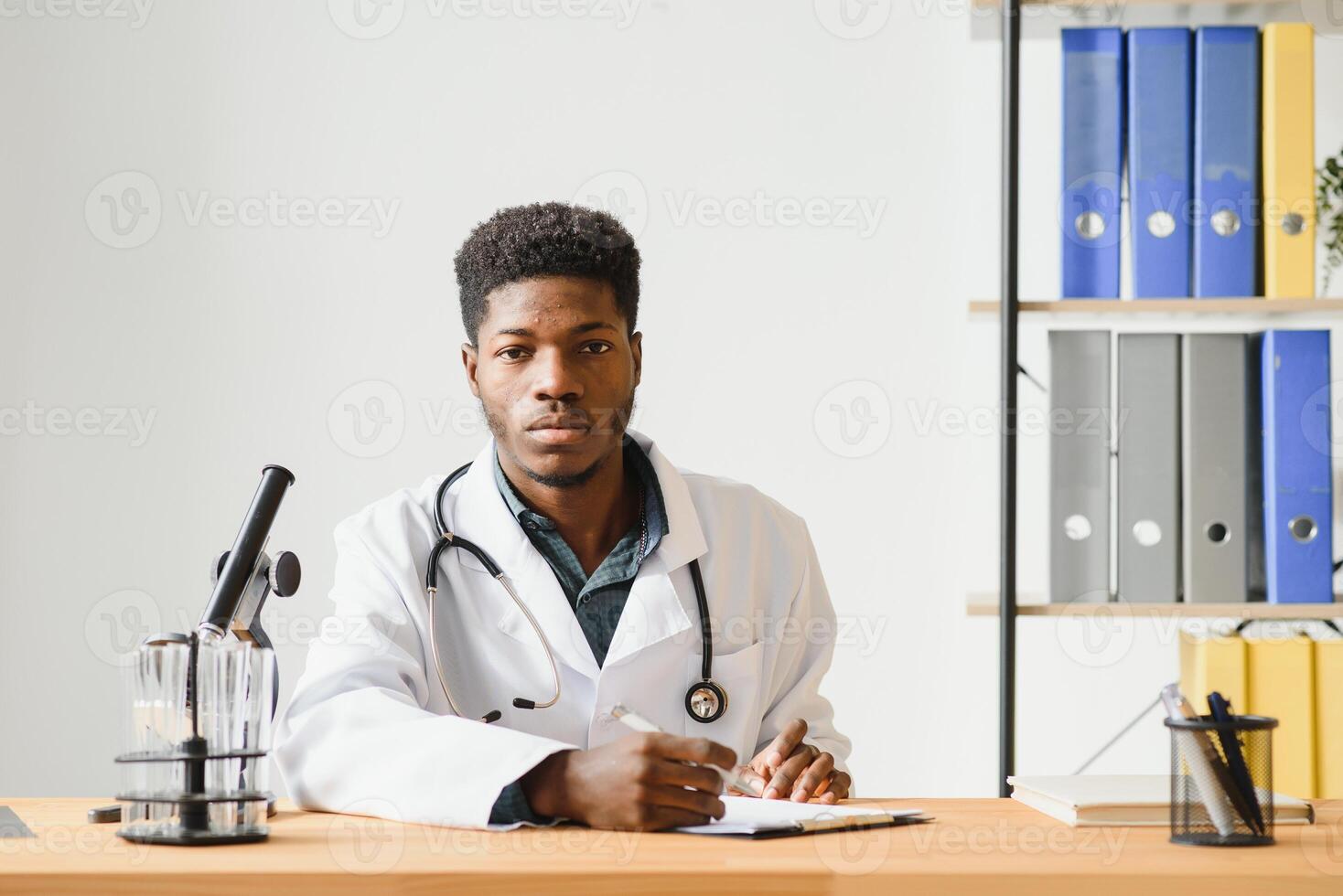 Portrait of young African-American man looking in microscope while working on medical research in laboratory, copy space. photo