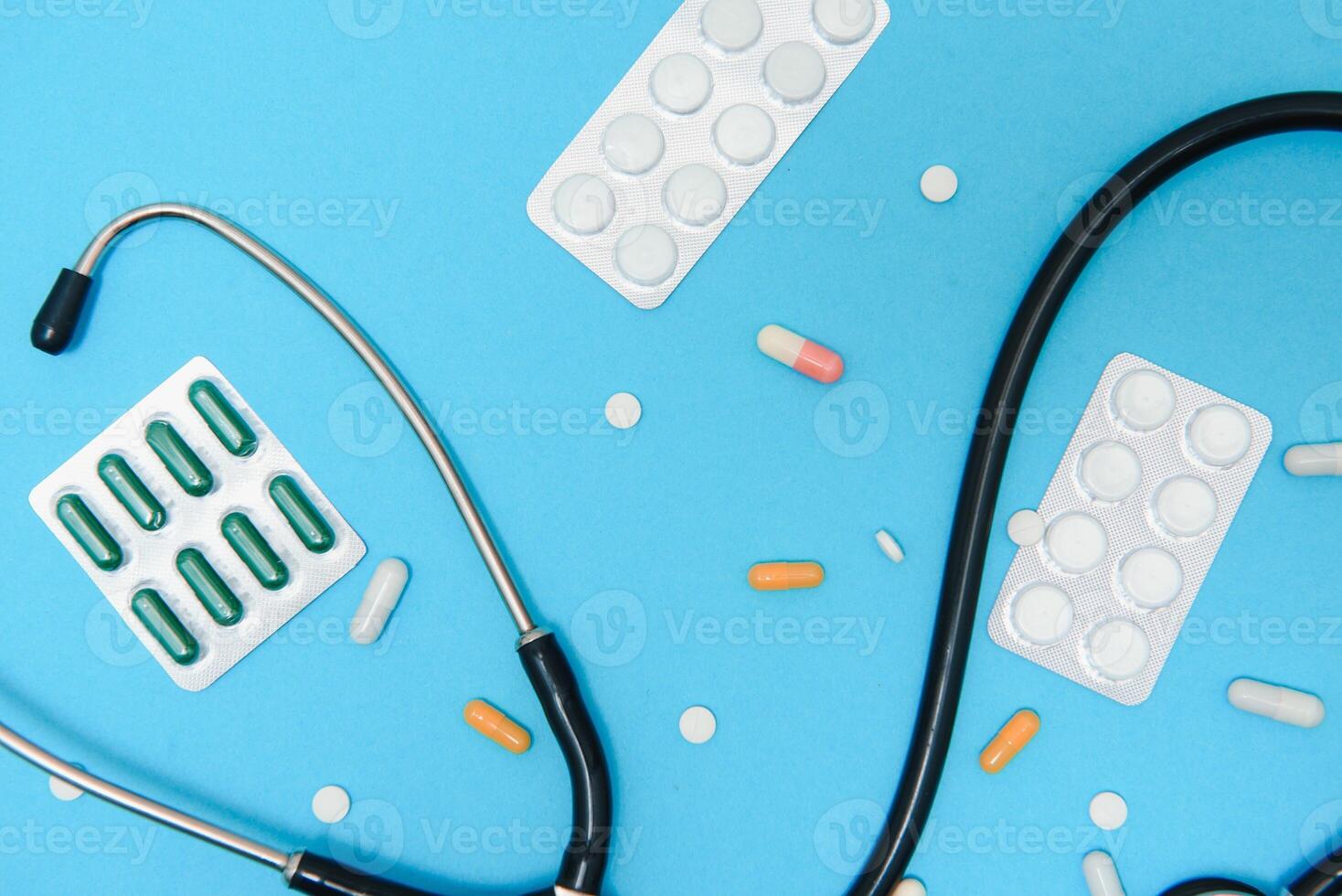 Top view of medicines, work tools and accessories doctor, nurse. Medical set - Tablets, thermometer, syringe, ampoules, adhesive plaster and statoscope on a blue background. Flat lay. photo