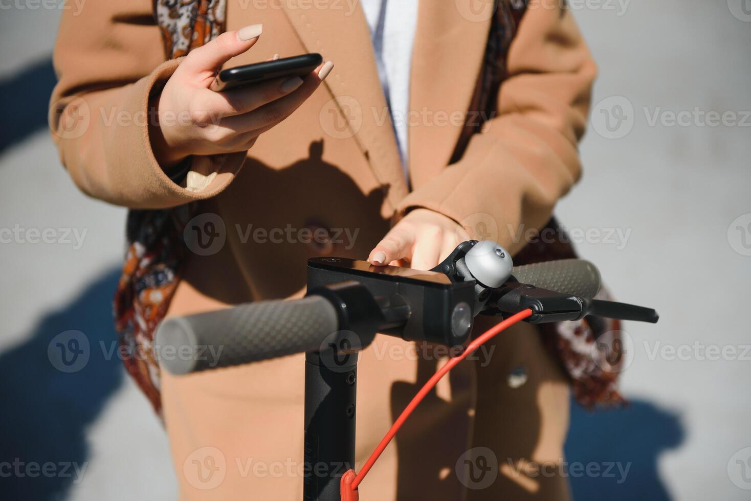 a young woman unlocks an e-scooter with her mobile phone photo