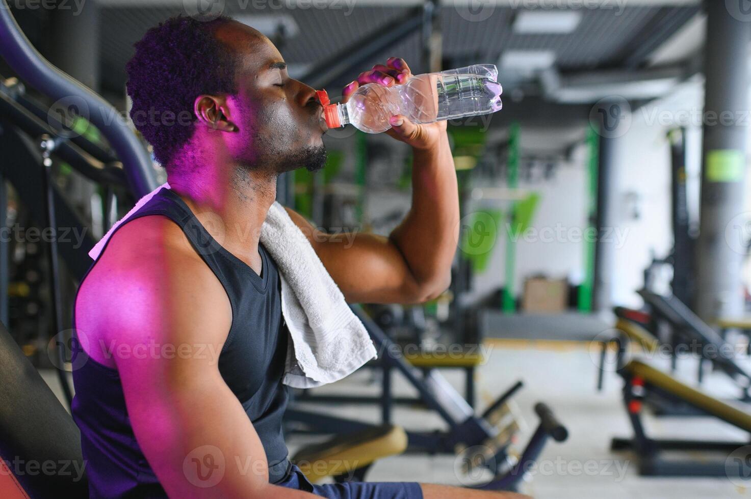 African american bodybuilder holding mug with water at modern gym photo