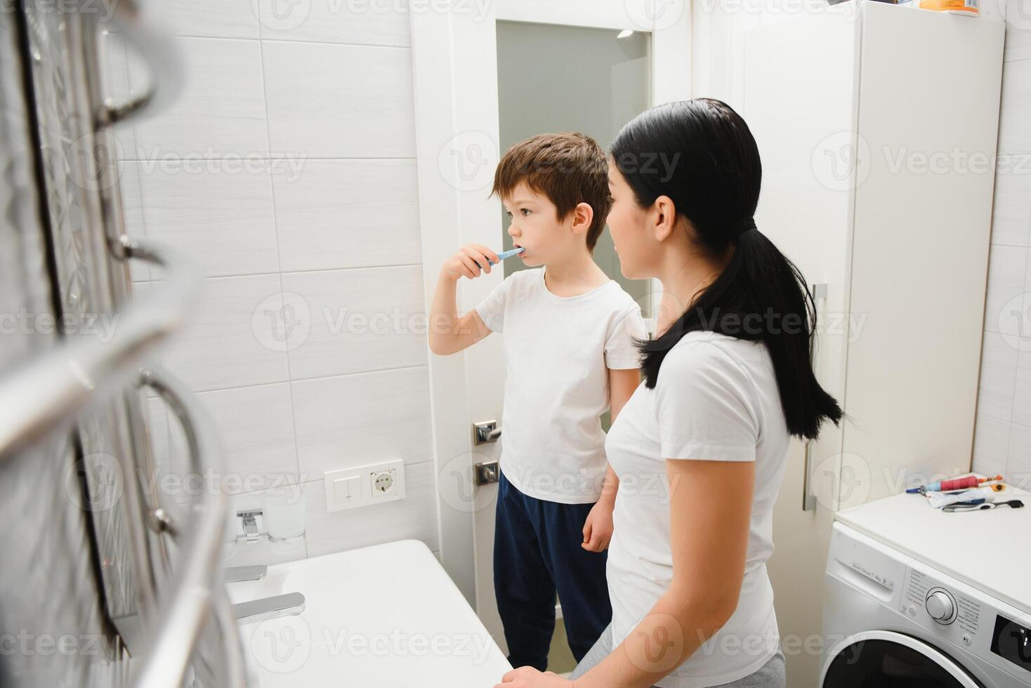 cute mother teaching kid boy teeth brushing photo