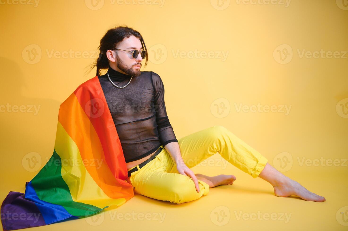 Gay man hold rainbow striped flag isolated on colored background studio portrait. People lifestyle fashion lgbtq concept photo